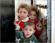 Photo of 3 small Palestinian children looking through a door.