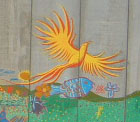 A large yellow bird has been painted on the wall between the Aamer home and their village.