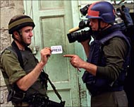Photo of an Israeli soldier checking a cameraman&rsquo;s press card.