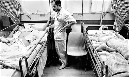 A doctor stands between two severely injured young men:
Fadi Mohammed, 18, (left) is paralyzed in both legs.